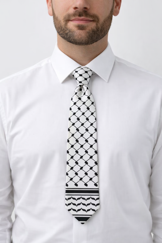 Man wearing a white shirt with a black and white keffiyeh inspired tie